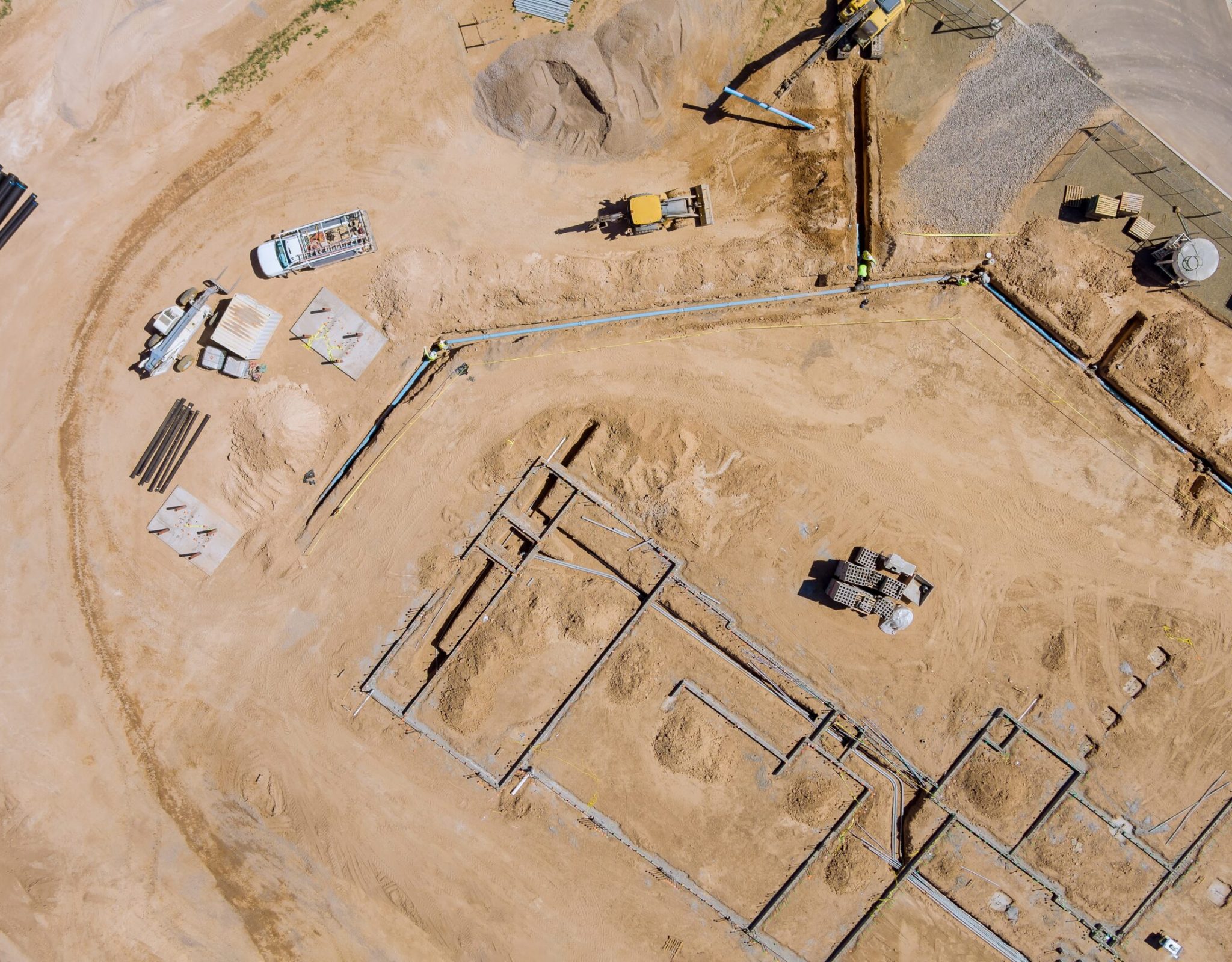 View of a large construction site where earthmoving equipment the ground to laying underground lay pipes residential buildings.